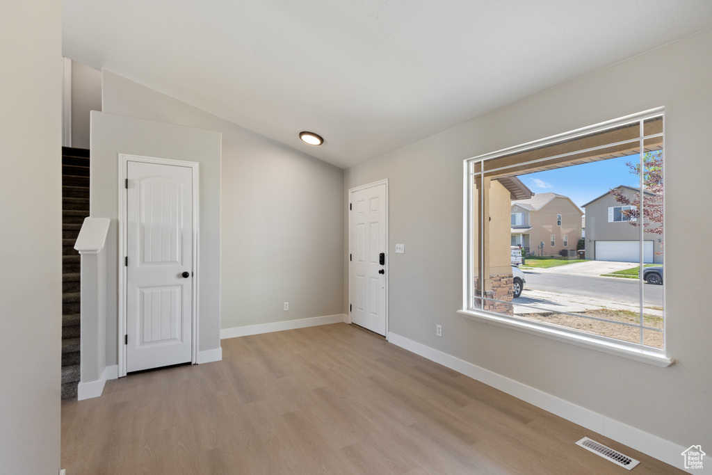 Foyer featuring wood finished floors, plenty of natural light, stairway, and vaulted ceiling