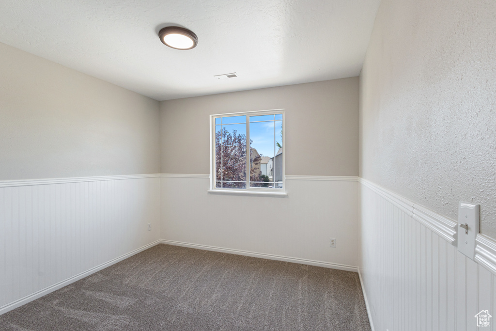 Unfurnished room with carpet and a wainscoted wall