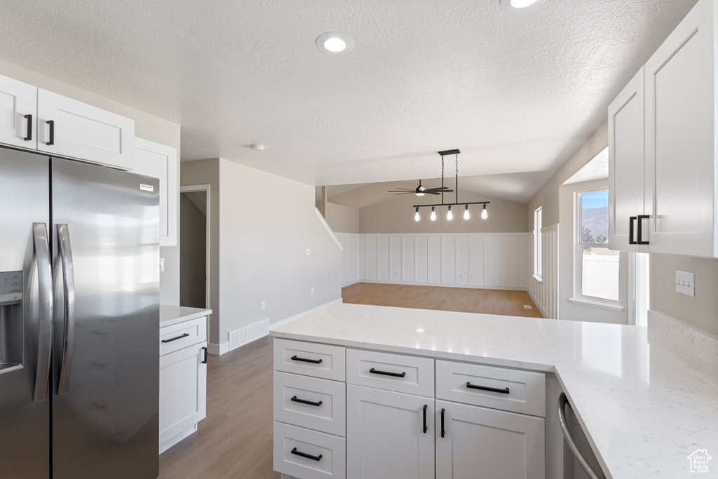 Kitchen featuring appliances with stainless steel finishes, ceiling fan, light wood-type flooring, a peninsula, and white cabinetry