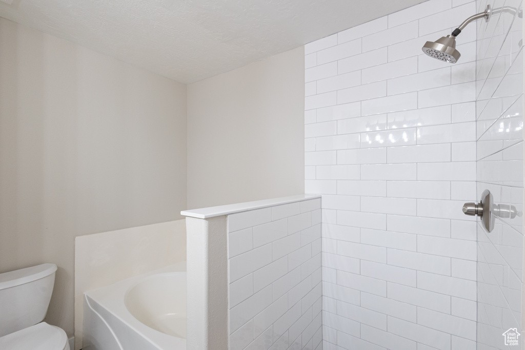 Bathroom featuring a tile shower, a garden tub, and a textured ceiling