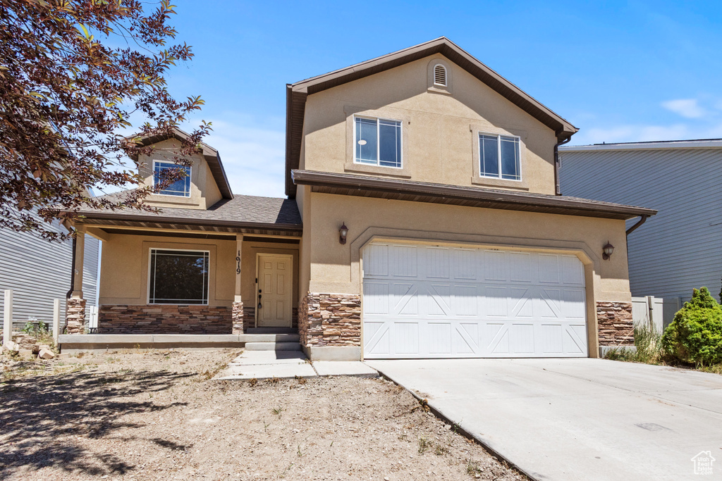 View of front facade with stone siding, stucco siding, and a garage