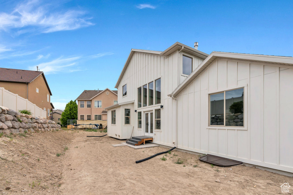 Back of house with board and batten siding, french doors, and a residential view