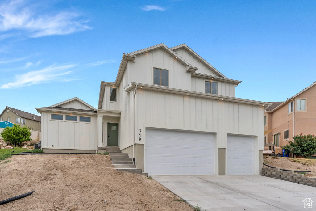 View of front of property with concrete driveway, an attached garage, and board and batten siding