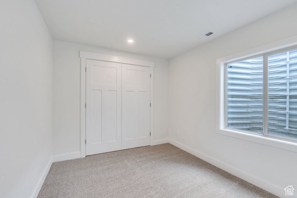Unfurnished bedroom with carpet flooring, a closet, and recessed lighting