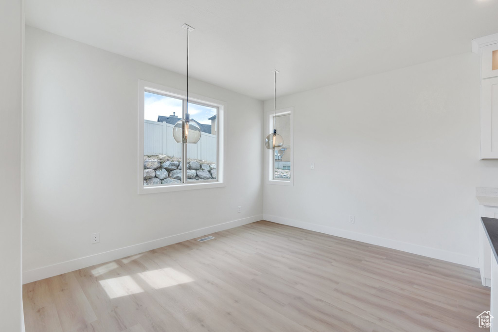 Unfurnished dining area with light wood finished floors and baseboards