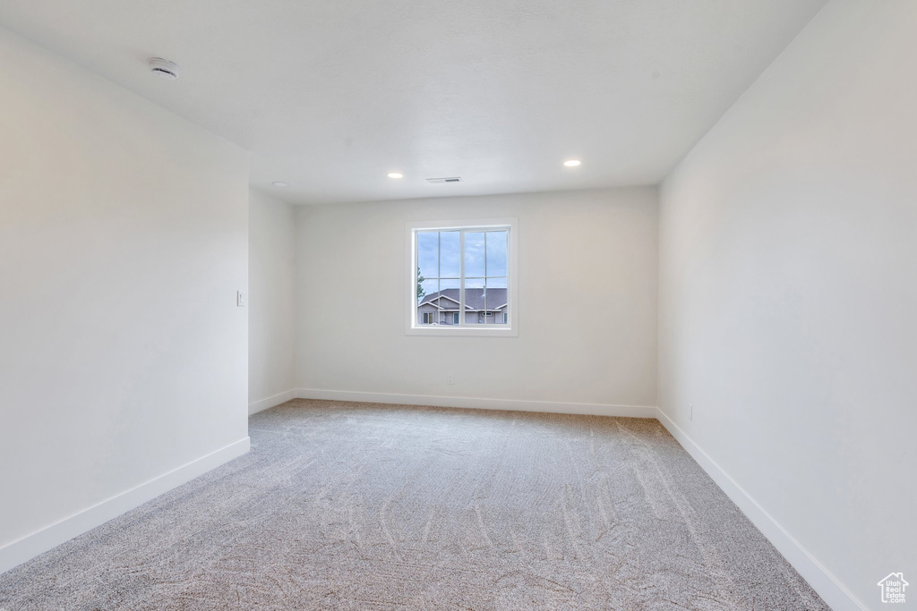 Empty room featuring carpet floors, a smoke detector, and recessed lighting