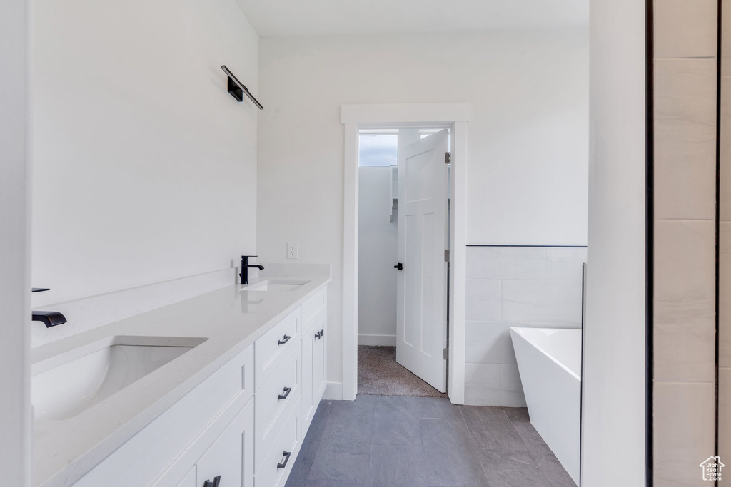 Full bath with a soaking tub, double vanity, and tile patterned flooring