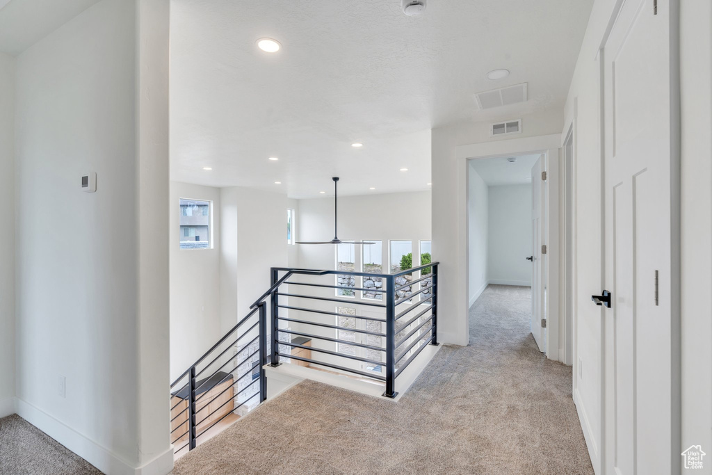 Hall featuring an upstairs landing, light colored carpet, and recessed lighting