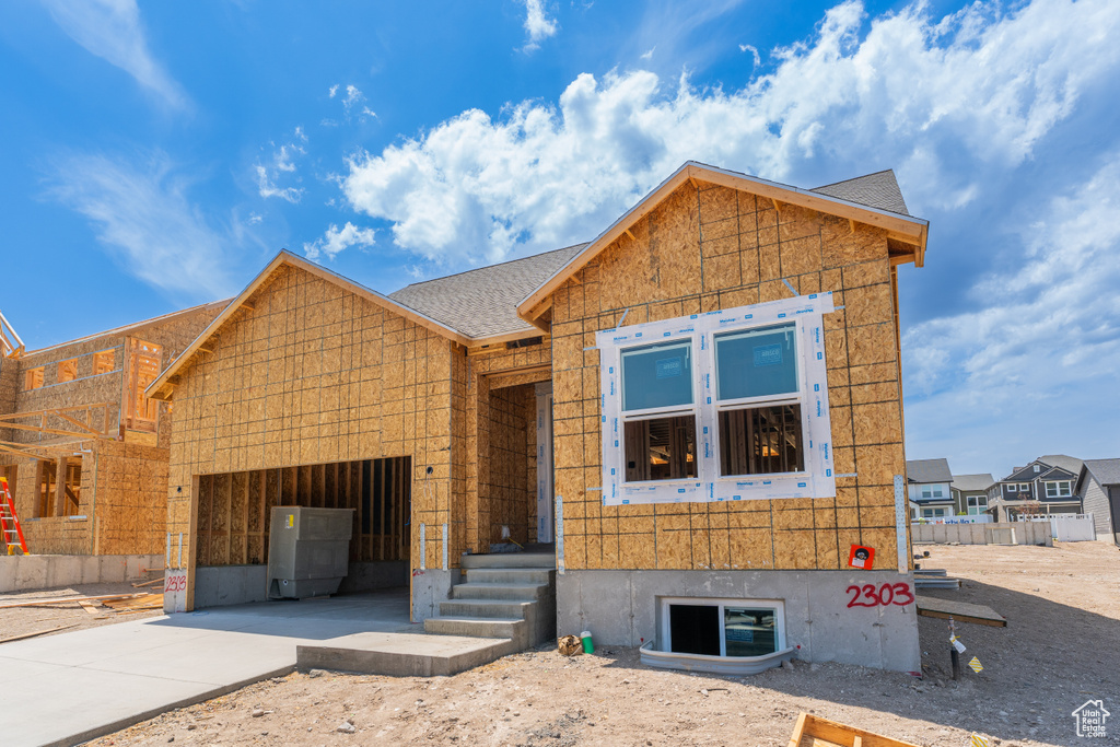 Unfinished property featuring driveway, a garage, and a shingled roof
