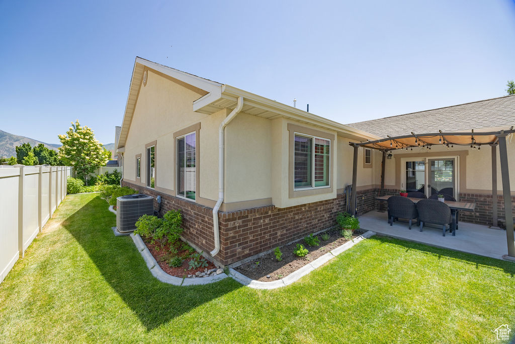 View of side of property featuring brick siding, stucco siding, a fenced backyard, an outdoor hangout area, and a patio
