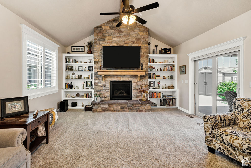 Living area featuring ceiling fan, carpet floors, vaulted ceiling, and a fireplace