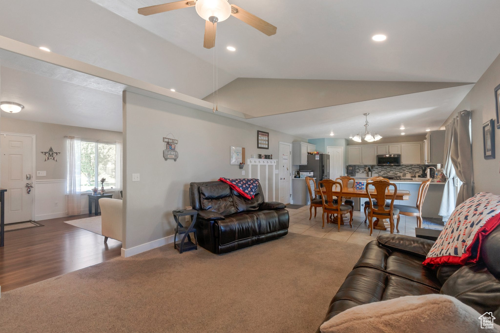 Living area with lofted ceiling, light carpet, a ceiling fan, a chandelier, and recessed lighting