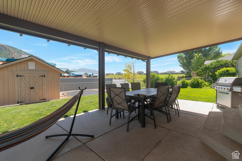 Fenced backyard with outdoor dining space, a patio, a storage shed, grilling area, and a residential view