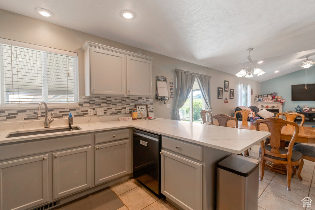 Kitchen featuring dishwashing machine, a peninsula, open floor plan, light tile patterned flooring, and lofted ceiling