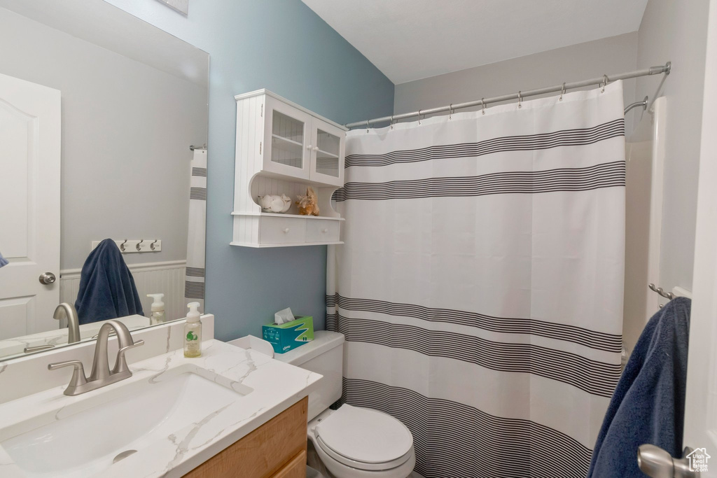 Bathroom featuring vanity, a wainscoted wall, and curtained shower