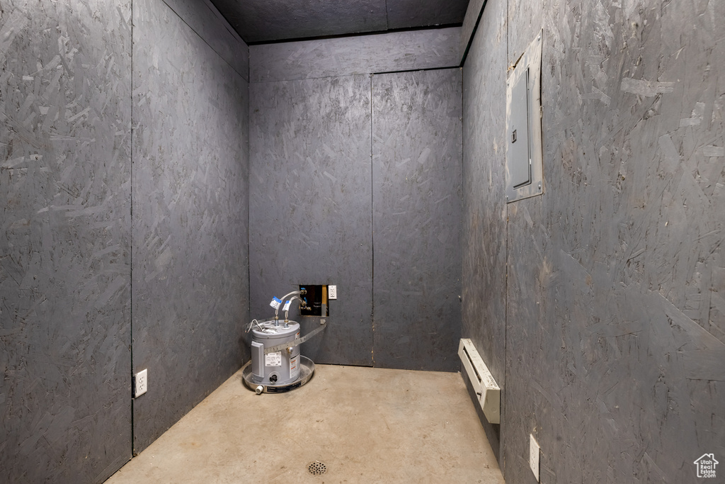 Detailed view of baseboard heating, electric panel, and unfinished concrete flooring