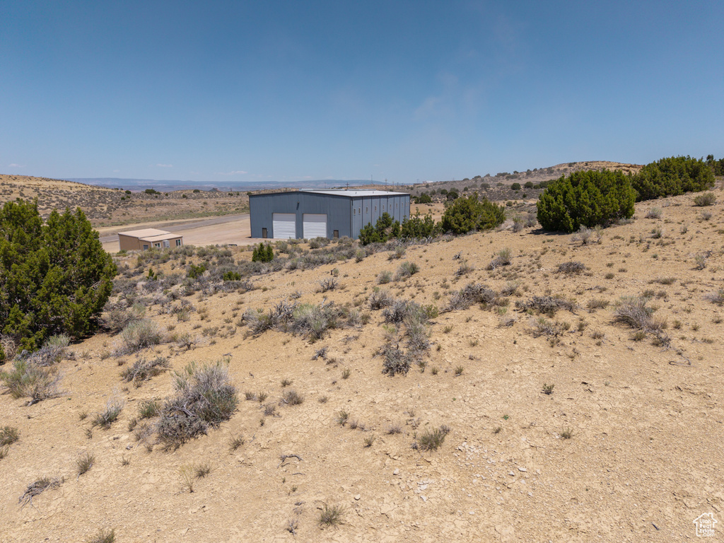 View of yard with a detached garage, view of desert landscape, and an outdoor structure