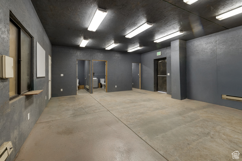 Empty room with a baseboard heating unit, concrete floors, and washer / dryer