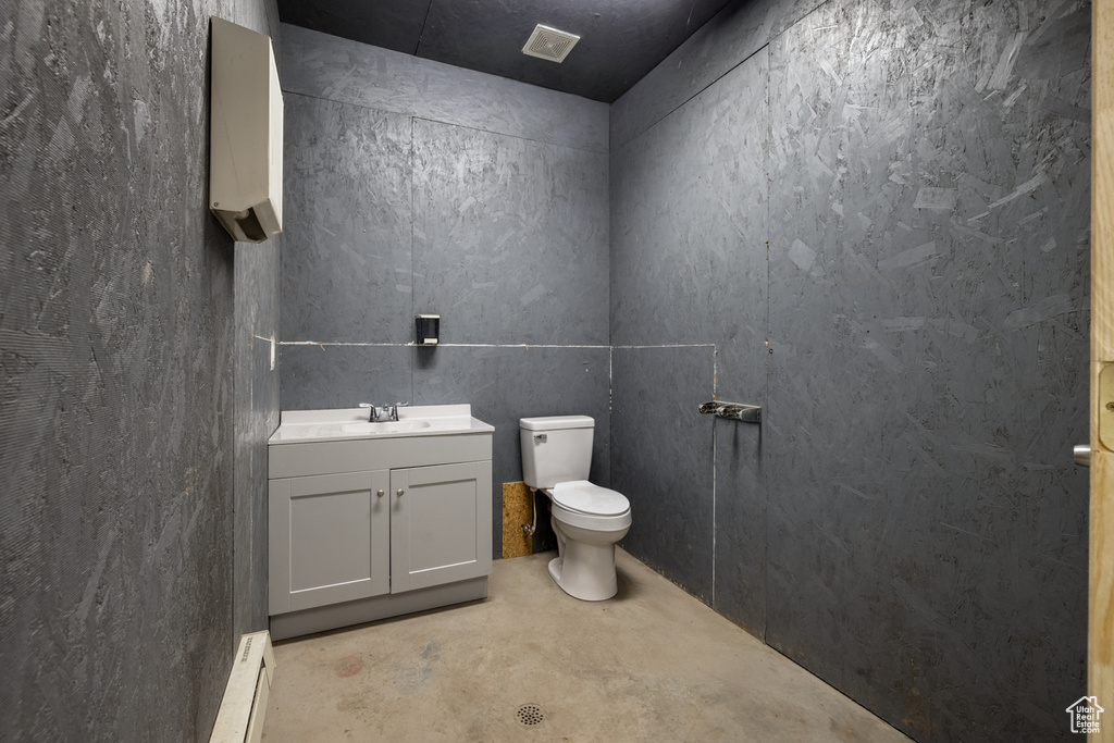 Bathroom with concrete flooring, vanity, and baseboard heating