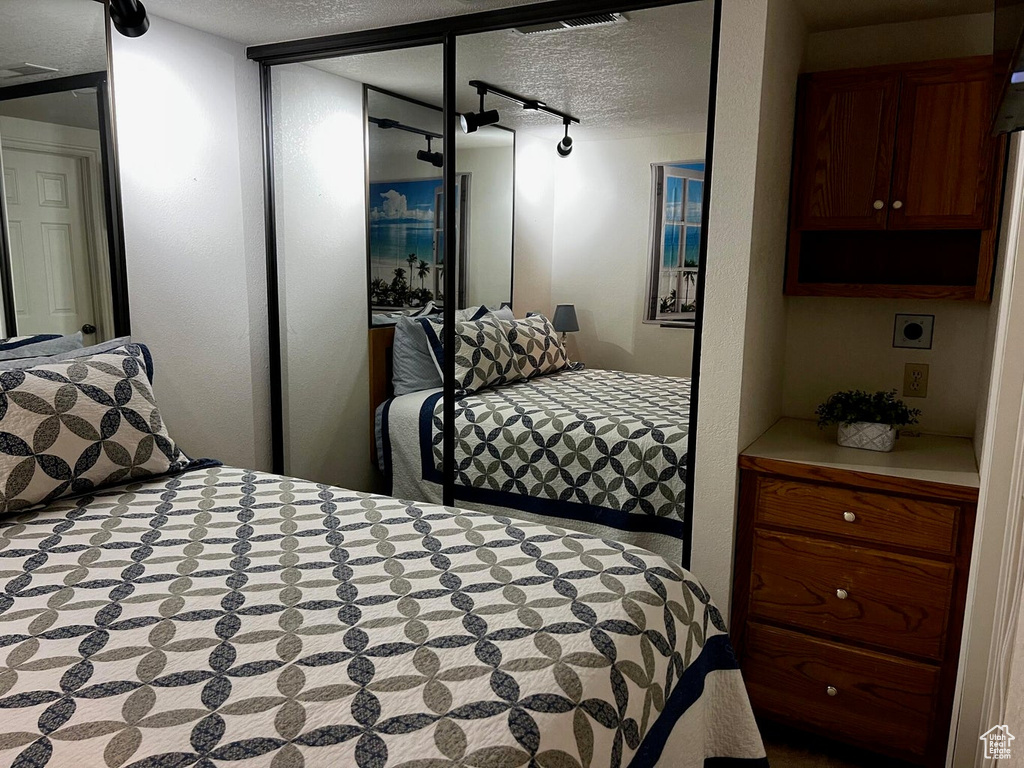 Bedroom with a textured ceiling and rail lighting