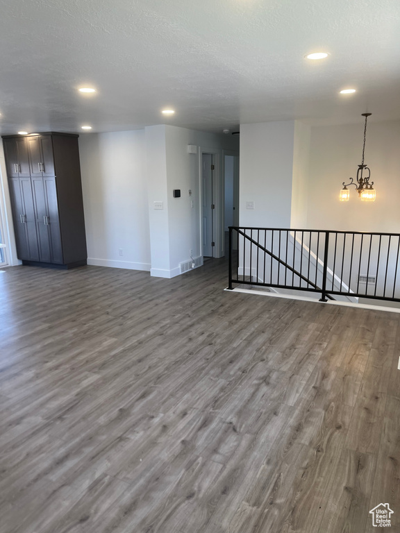 Empty room with wood finished floors, recessed lighting, a textured ceiling, and a chandelier