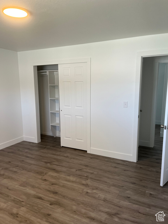Unfurnished bedroom featuring dark wood finished floors and a closet