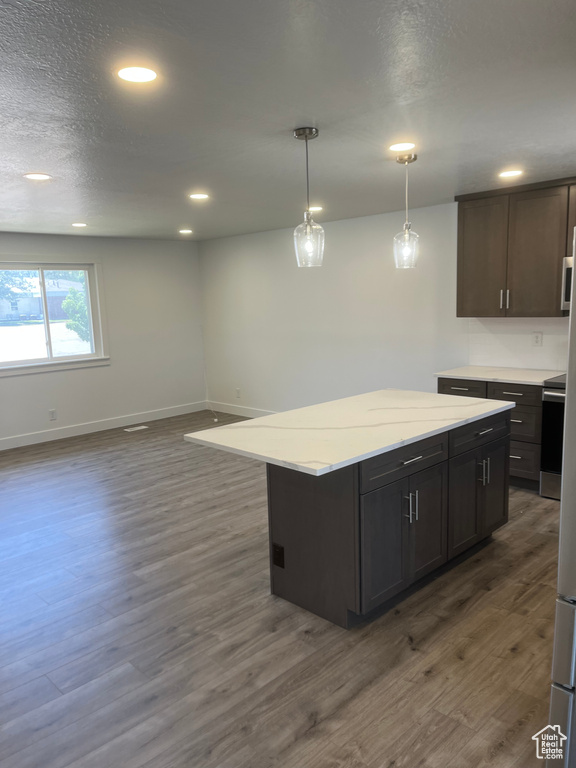 Kitchen with dark wood finished floors, recessed lighting, decorative light fixtures, a center island, and range