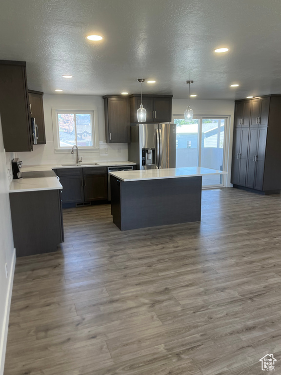 Kitchen featuring stainless steel fridge with ice dispenser, plenty of natural light, a kitchen island, wood finished floors, and a textured ceiling