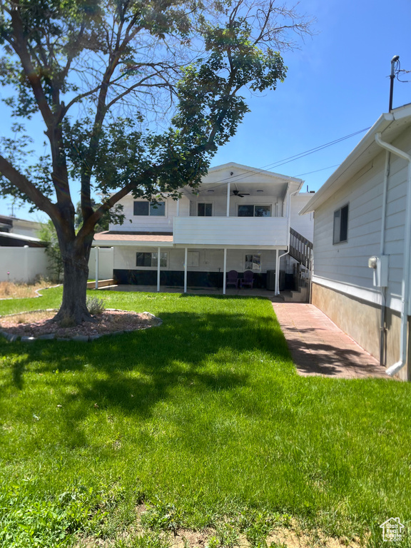 Back of property with ceiling fan and a lawn