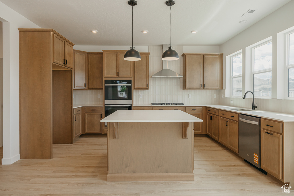 Kitchen with stainless steel dishwasher, double wall oven, a center island, light wood-style floors, and decorative backsplash