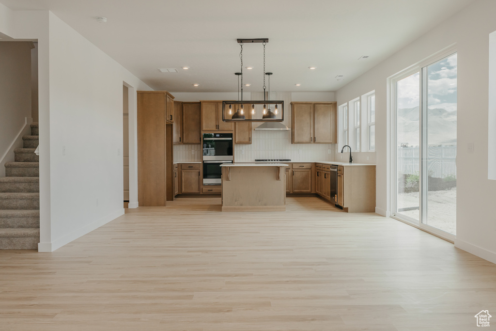 Kitchen with light wood-type flooring, appliances with stainless steel finishes, healthy amount of natural light, tasteful backsplash, and recessed lighting