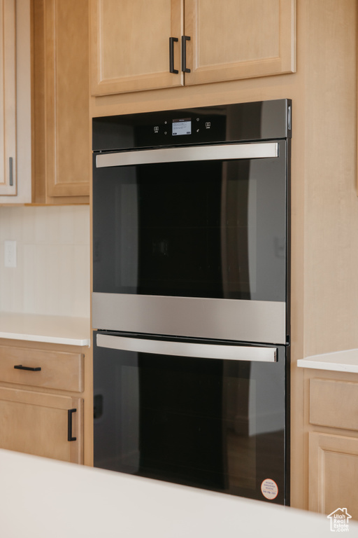 Kitchen view of multiple ovens, light brown cabinets, decorative backsplash, and light countertops