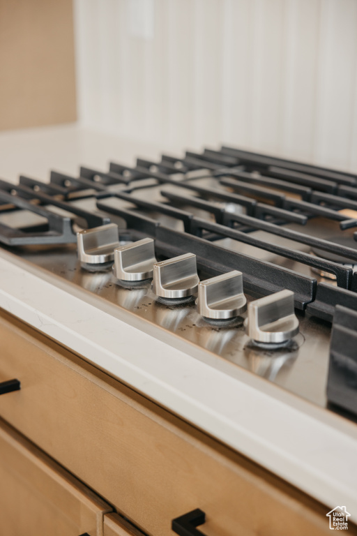 Kitchen view of light countertops and stainless steel gas cooktop
