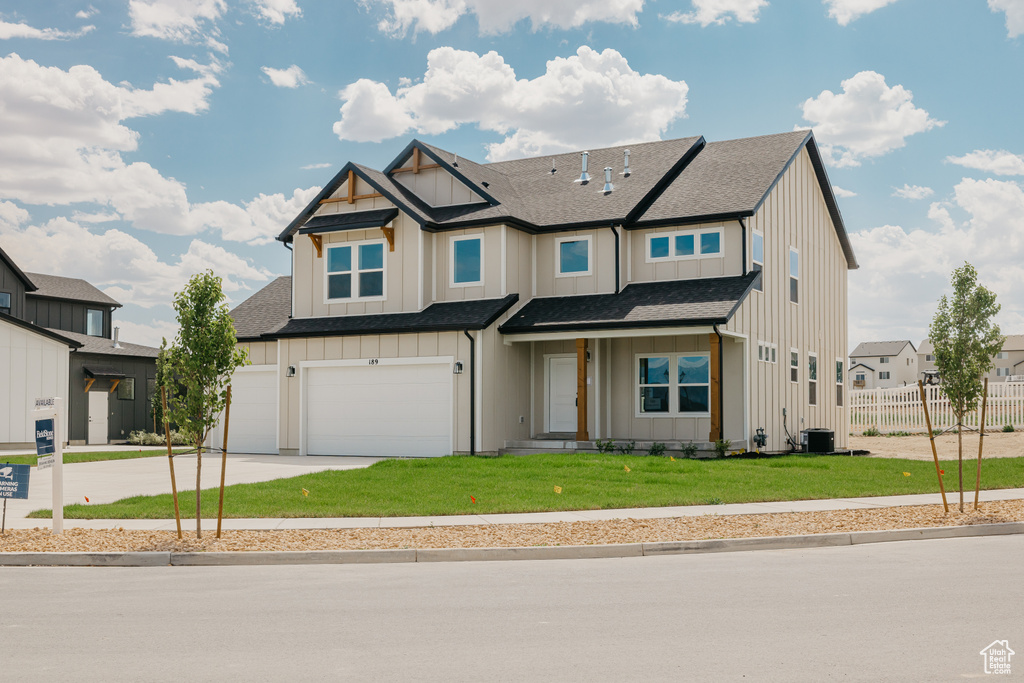 View of front of property featuring board and batten siding, driveway, a garage, and a shingled roof