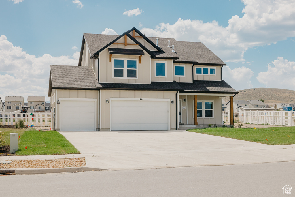View of front of property featuring board and batten siding, driveway, an attached garage, a mountain view, and roof with shingles