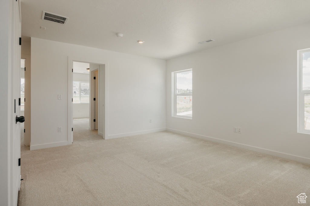 Spare room featuring light carpet and a smoke detector