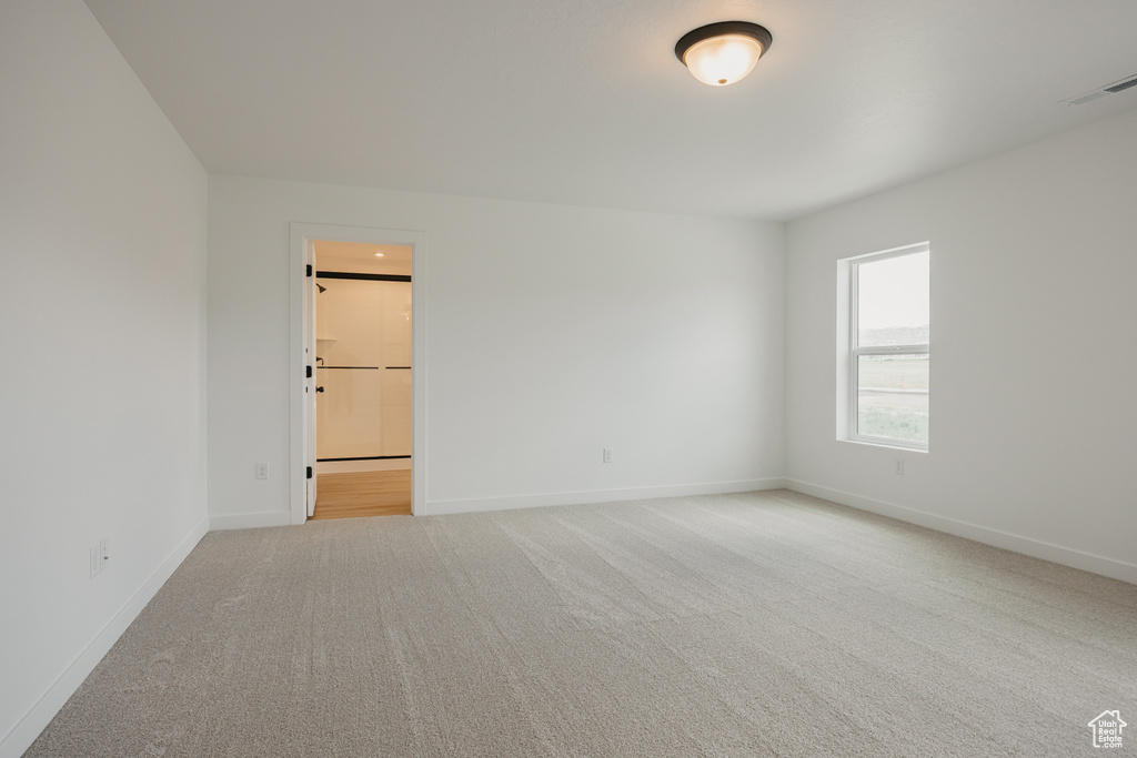 Spare room featuring carpet flooring and baseboards