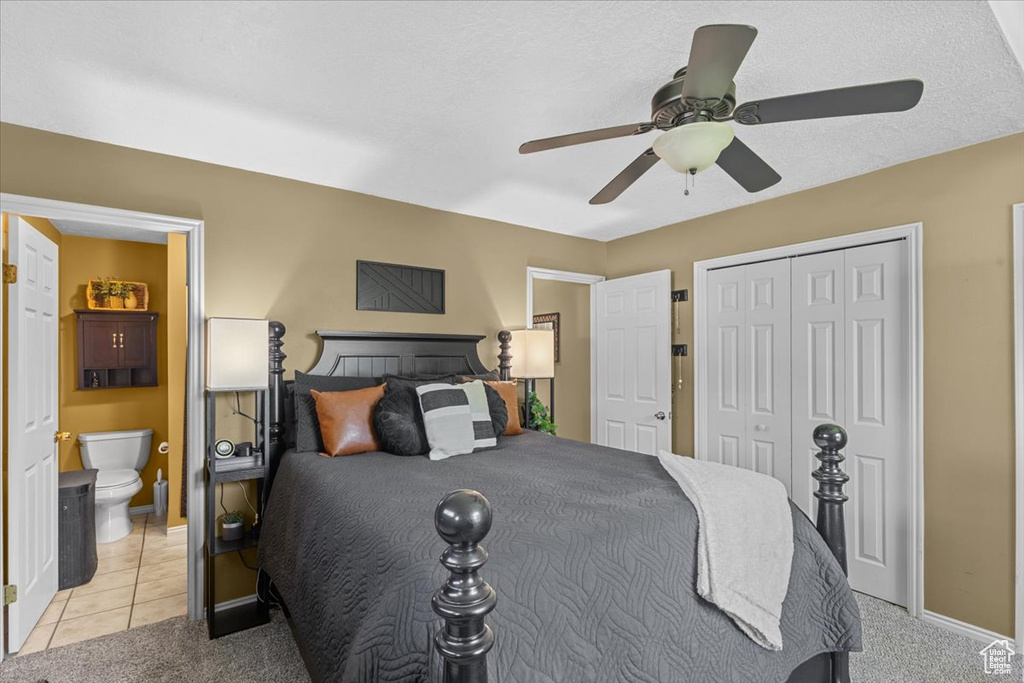 Bedroom with light colored carpet, a closet, ensuite bath, and ceiling fan