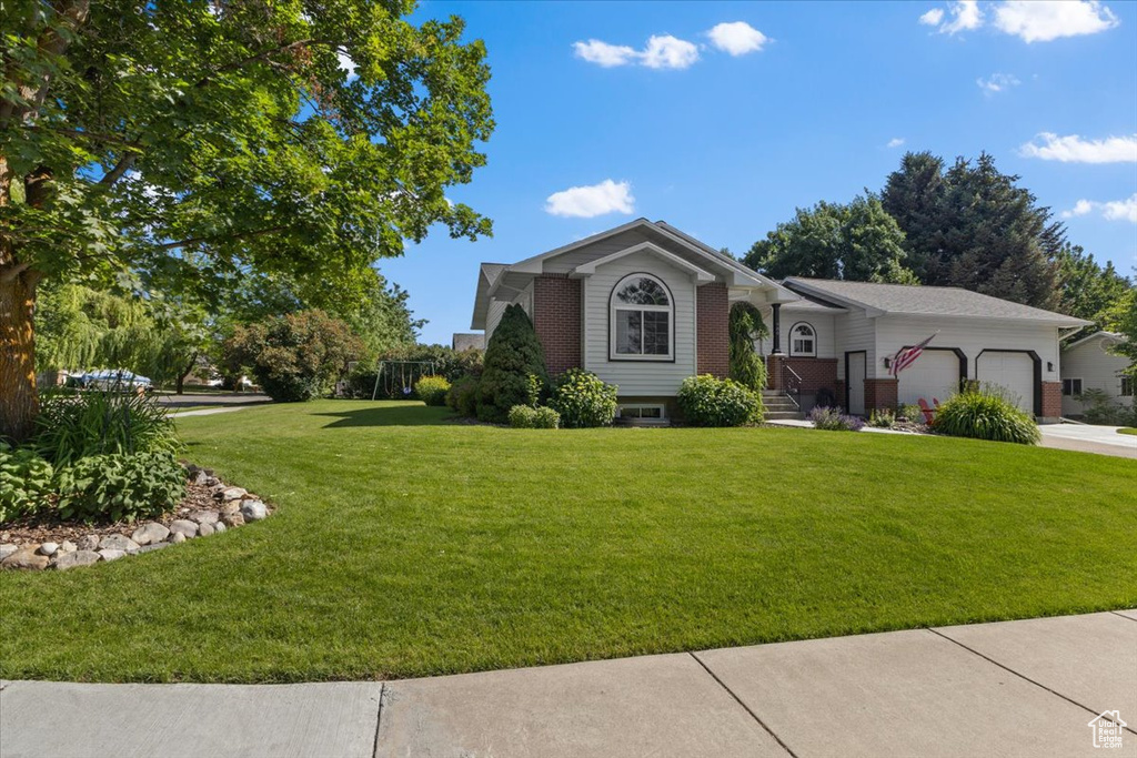 View of front of property with an attached garage, a front yard, and concrete driveway