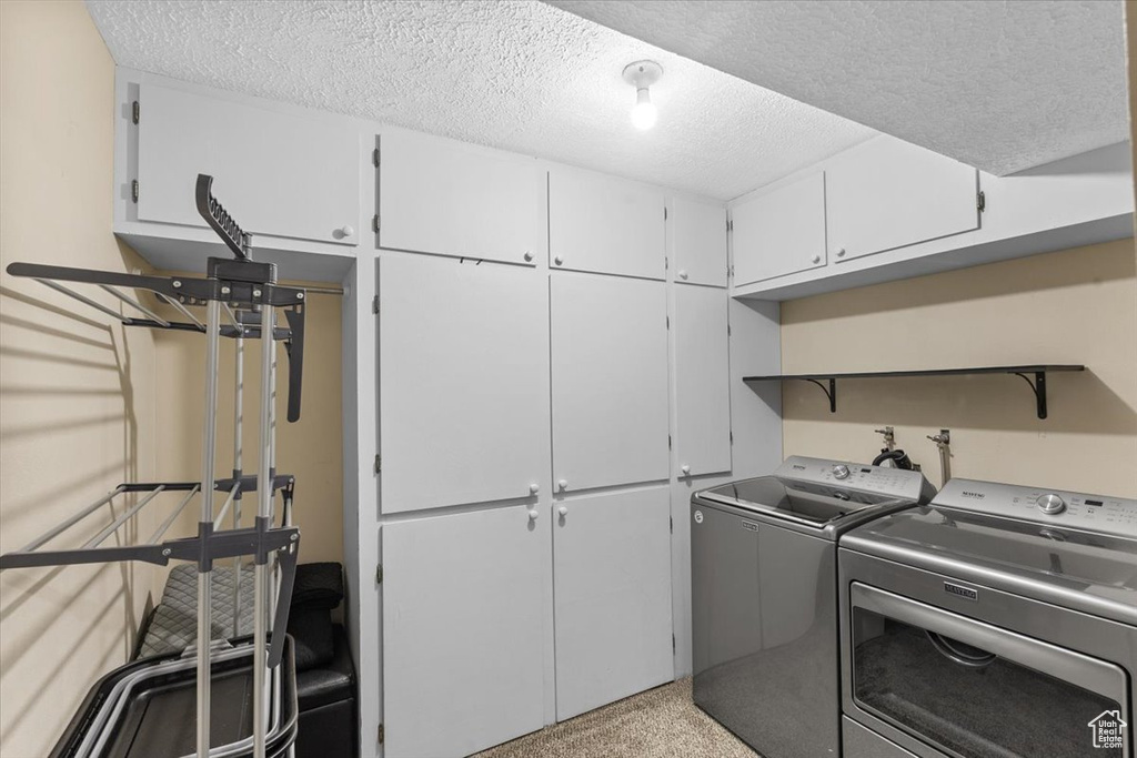 Laundry room with cabinet space, independent washer and dryer, and a textured ceiling