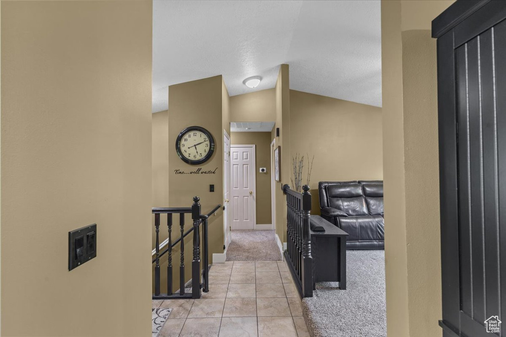 Entryway with light colored carpet, light tile patterned floors, and vaulted ceiling