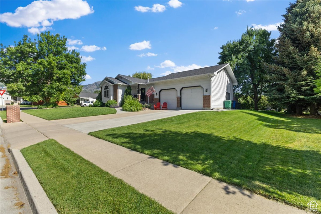 Ranch-style house featuring an attached garage, a front lawn, and driveway