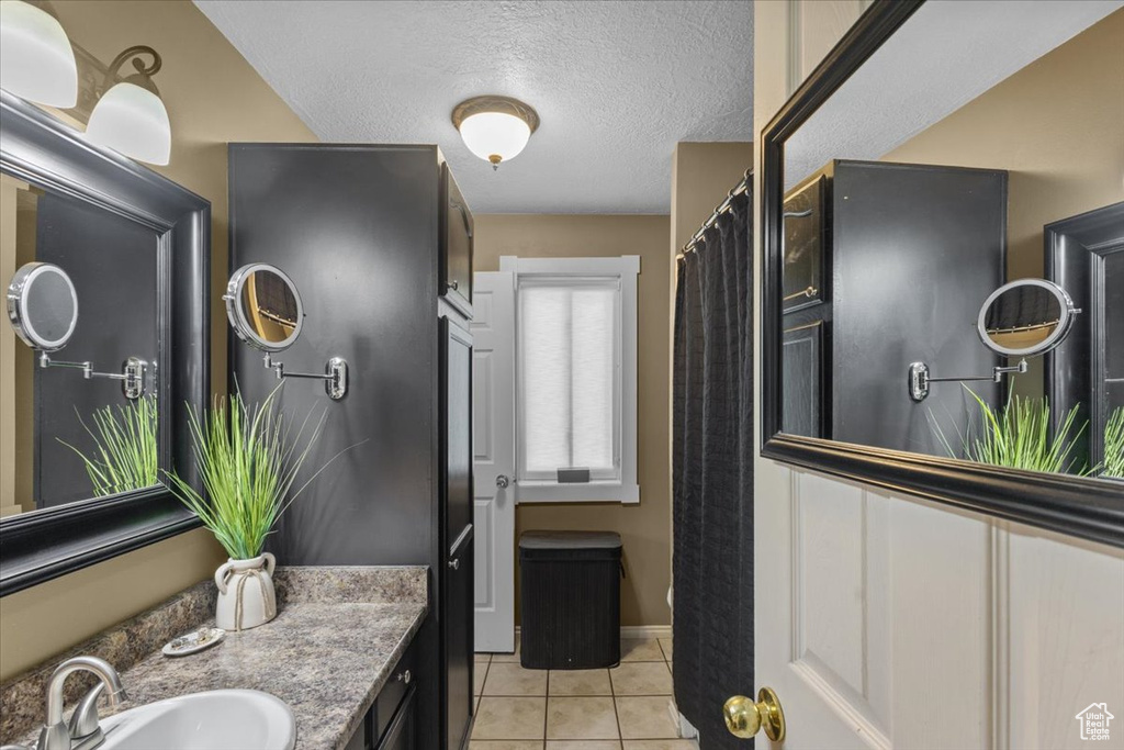 Bathroom featuring tile patterned floors, vanity, and a textured ceiling