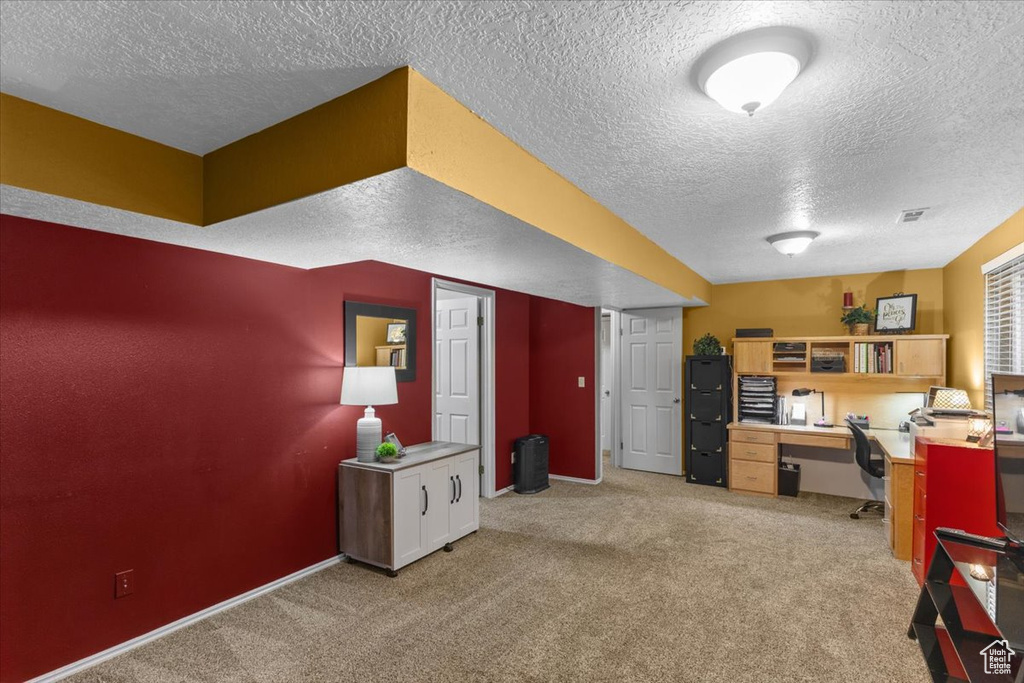 Office space with a textured ceiling and light carpet