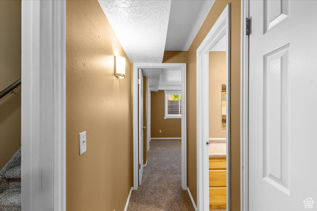 Corridor with a textured ceiling and carpet floors