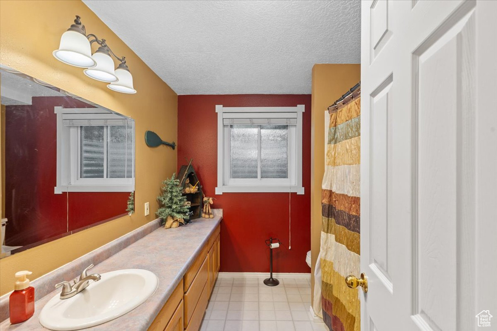 Bathroom with vanity, a textured ceiling, and curtained shower