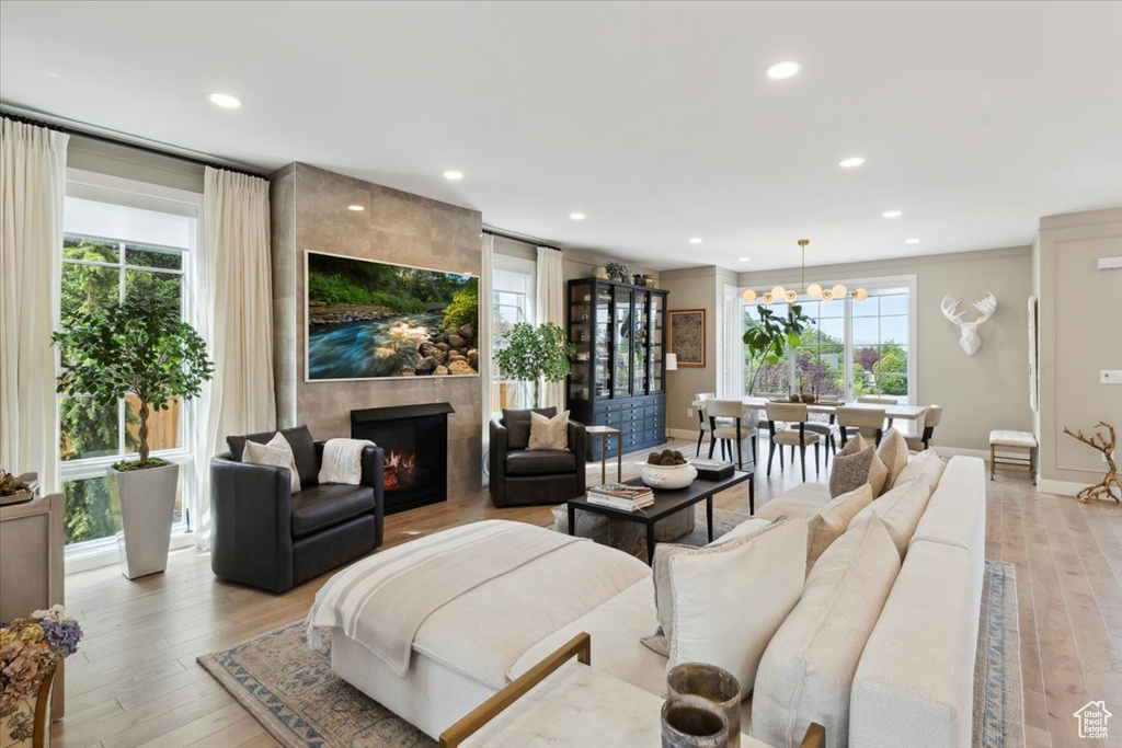 Living room featuring plenty of natural light, recessed lighting, a tiled fireplace, light wood-style floors, and a chandelier