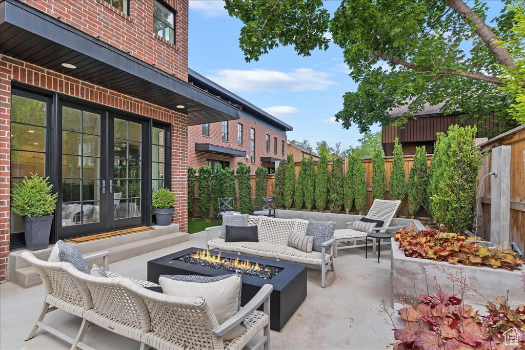 Fenced backyard featuring french doors, a patio, and an outdoor living space with a fire pit