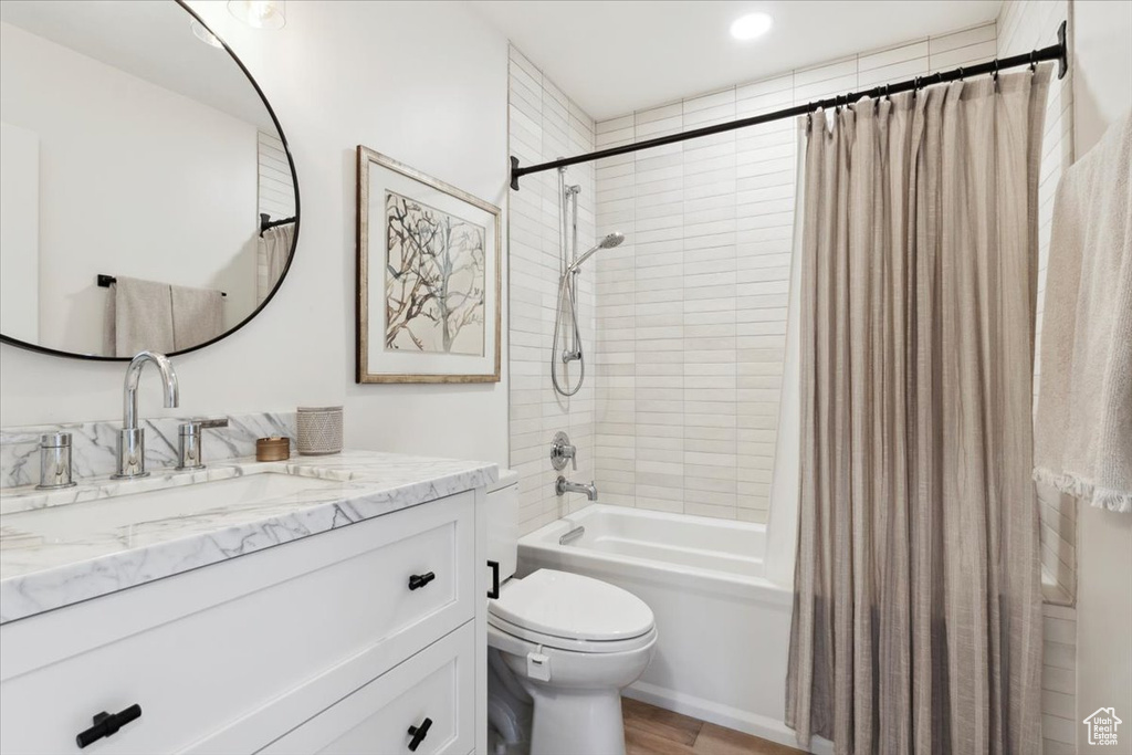 Bathroom featuring shower / tub combo, vanity, and wood finished floors