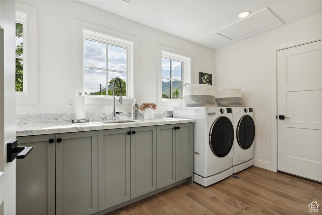 Washroom featuring washer and clothes dryer, light wood finished floors, cabinet space, and attic access